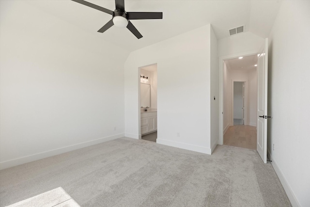 unfurnished bedroom featuring ensuite bathroom, light colored carpet, and ceiling fan