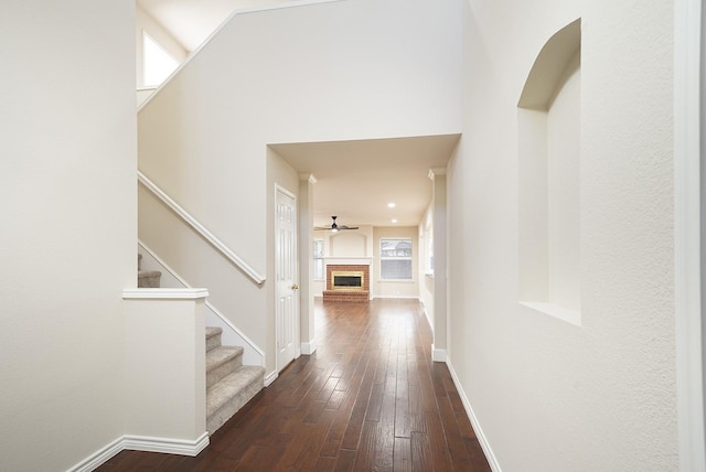 hall with a high ceiling, dark hardwood / wood-style flooring, and plenty of natural light