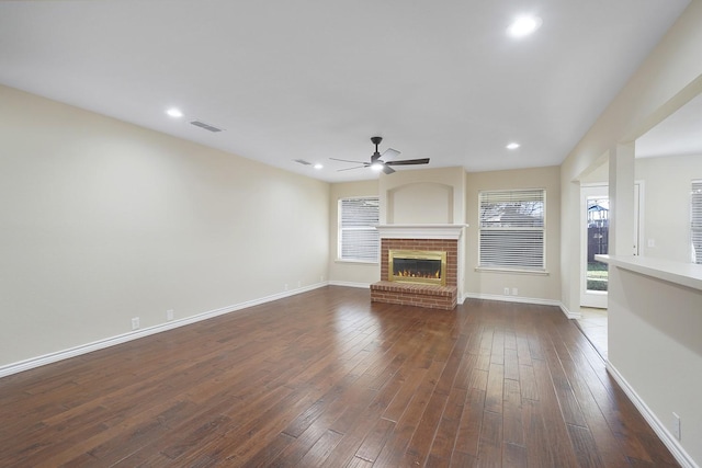 unfurnished living room featuring a brick fireplace, dark hardwood / wood-style flooring, and ceiling fan