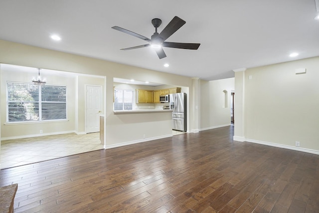 unfurnished living room featuring light wood-type flooring and ceiling fan with notable chandelier