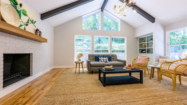 living room with vaulted ceiling with beams, a brick fireplace, an inviting chandelier, and light hardwood / wood-style flooring