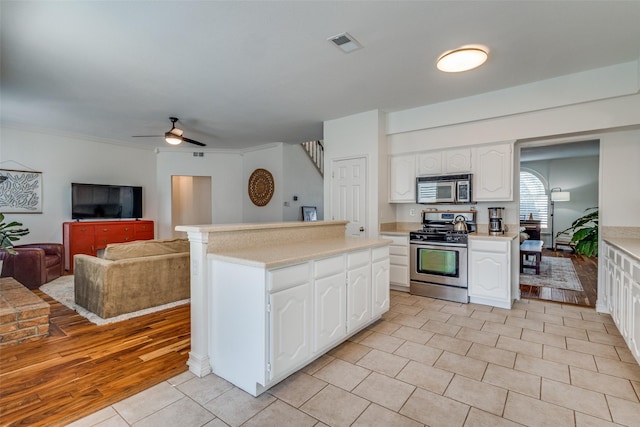 kitchen with ceiling fan, crown molding, white cabinetry, stainless steel appliances, and light tile patterned floors