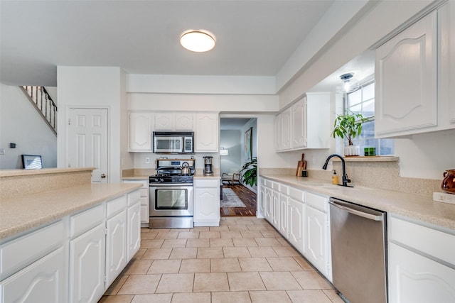 kitchen with sink, white cabinetry, appliances with stainless steel finishes, and light tile patterned flooring