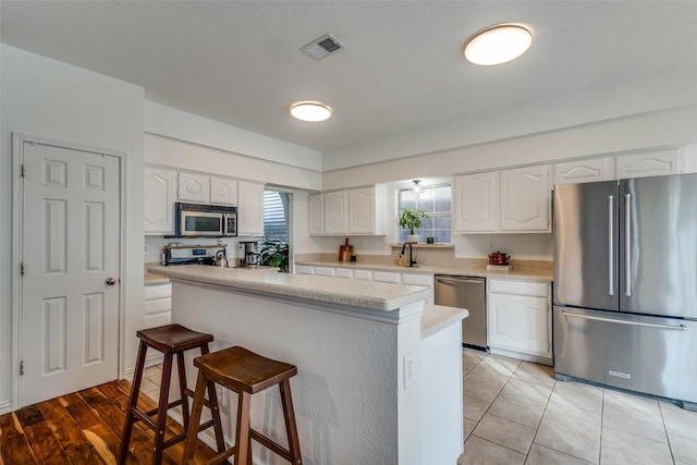 kitchen with white cabinets, a breakfast bar, sink, and stainless steel appliances