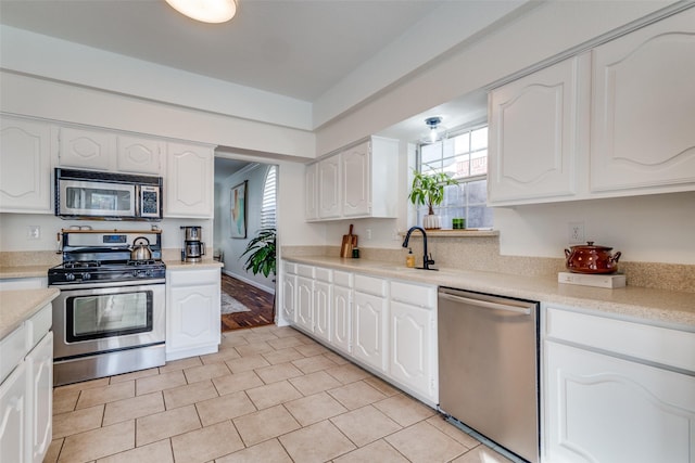 kitchen with light tile patterned floors, white cabinets, appliances with stainless steel finishes, and sink