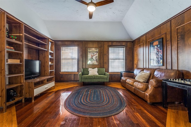 living room with wood walls, ceiling fan, dark hardwood / wood-style floors, lofted ceiling, and a textured ceiling