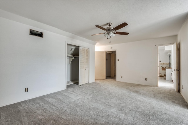 unfurnished bedroom featuring ceiling fan, a textured ceiling, a closet, and light carpet