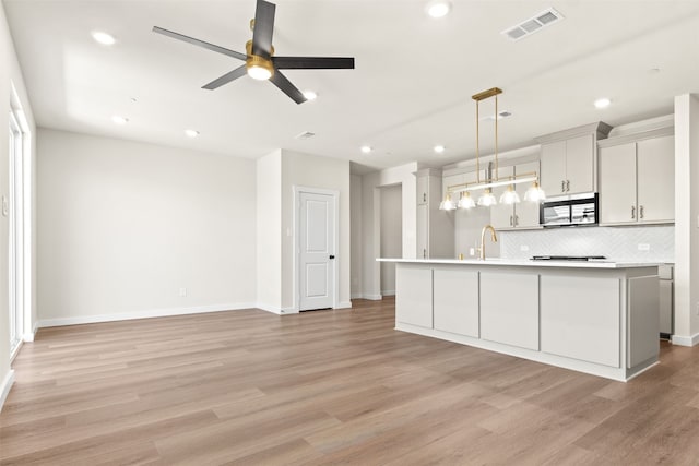 729 Tower Rd, Wylie, TX 75098 - kitchen with ceiling fan, a sink, light wood-style flooring, stainless steel microwave, and tasteful backsplash