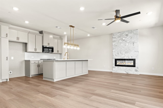 729 Tower Rd, Wylie, TX 75098 - kitchen with a ceiling fan, light wood-style floors, open floor plan, stainless steel microwave, and a sink