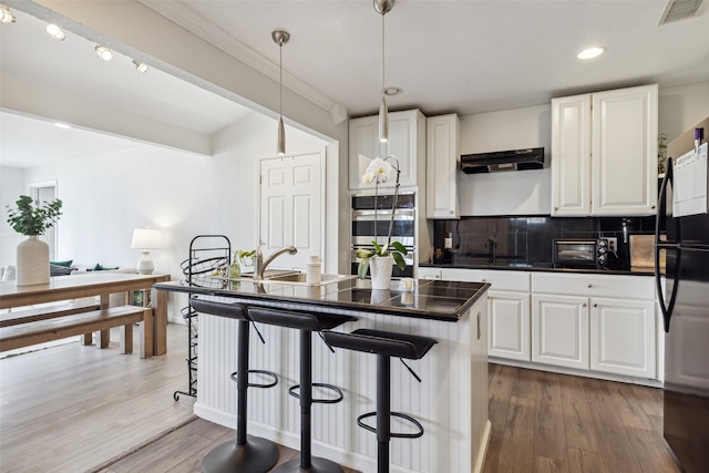 kitchen with dark countertops, pendant lighting, a kitchen island, white cabinetry, and freestanding refrigerator