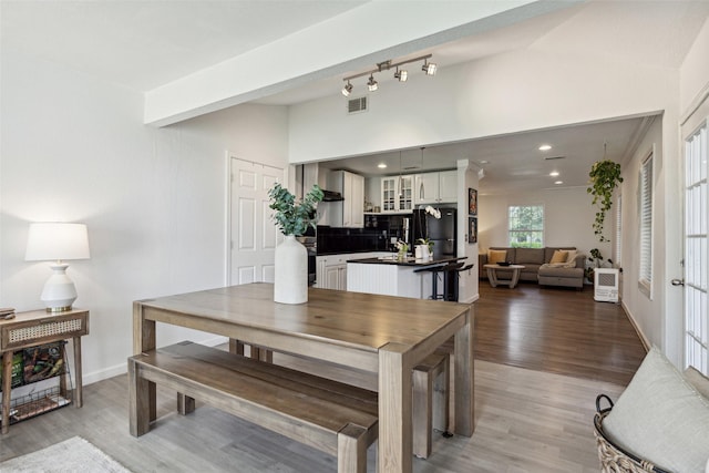 dining area featuring lofted ceiling, light wood-type flooring, baseboards, and visible vents