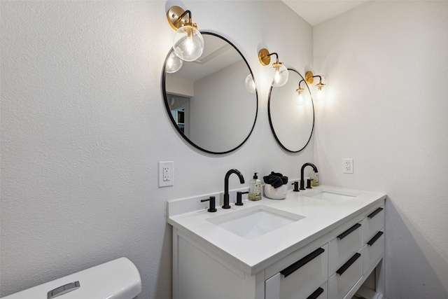 bathroom with double vanity, a sink, and toilet