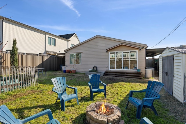 back of property with a storage shed, entry steps, fence, an outbuilding, and an outdoor fire pit