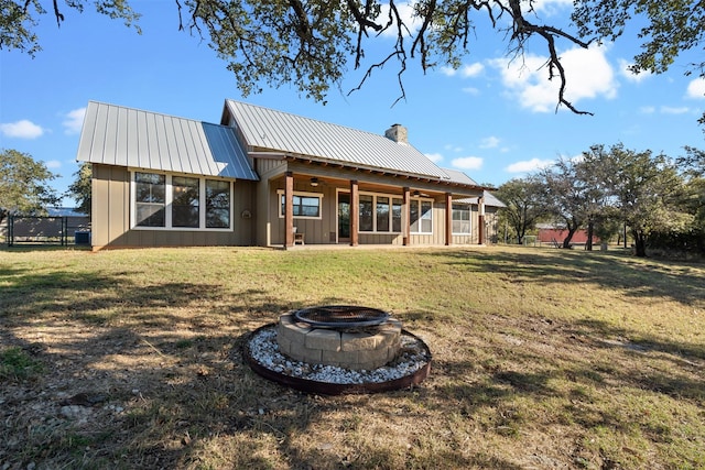 back of property with a lawn and an outdoor fire pit