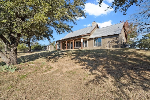 rear view of property featuring a lawn and a shed