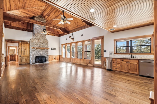 unfurnished living room with high vaulted ceiling, wooden ceiling, sink, and a stone fireplace