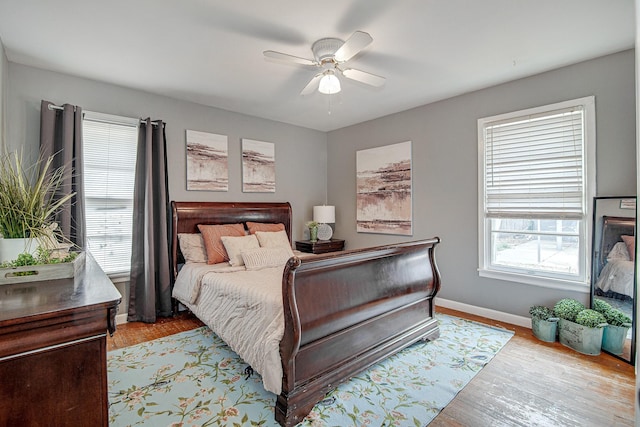 bedroom with ceiling fan, light hardwood / wood-style flooring, and multiple windows