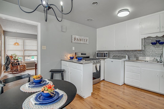 kitchen with washer / dryer, stainless steel appliances, white cabinets, and sink