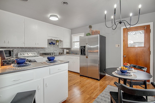 kitchen with a healthy amount of sunlight, decorative backsplash, appliances with stainless steel finishes, and white cabinetry