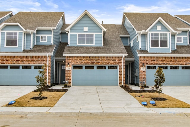 townhome / multi-family property with an attached garage, brick siding, concrete driveway, and roof with shingles