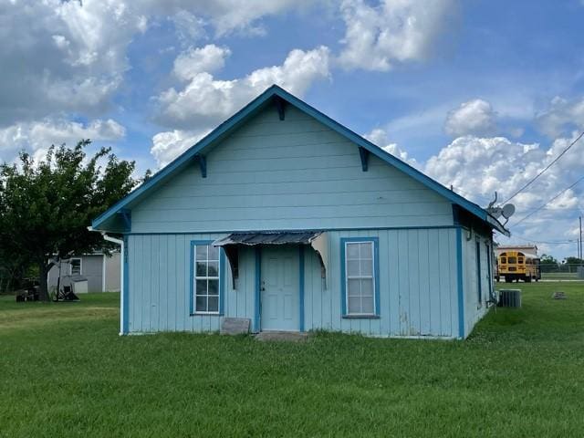 rear view of property with central AC and a yard