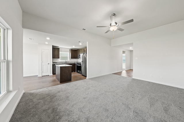 unfurnished living room featuring dark colored carpet, sink, and ceiling fan