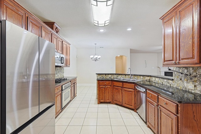 kitchen with light tile patterned floors, appliances with stainless steel finishes, tasteful backsplash, hanging light fixtures, and sink