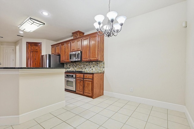 kitchen with light tile patterned floors, appliances with stainless steel finishes, decorative backsplash, a notable chandelier, and pendant lighting