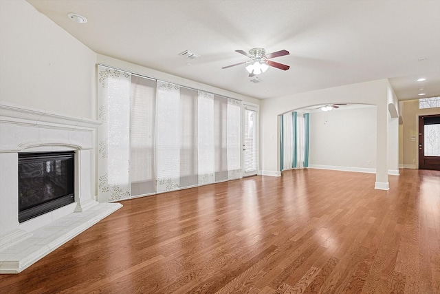 unfurnished living room featuring ceiling fan, hardwood / wood-style floors, and a tiled fireplace