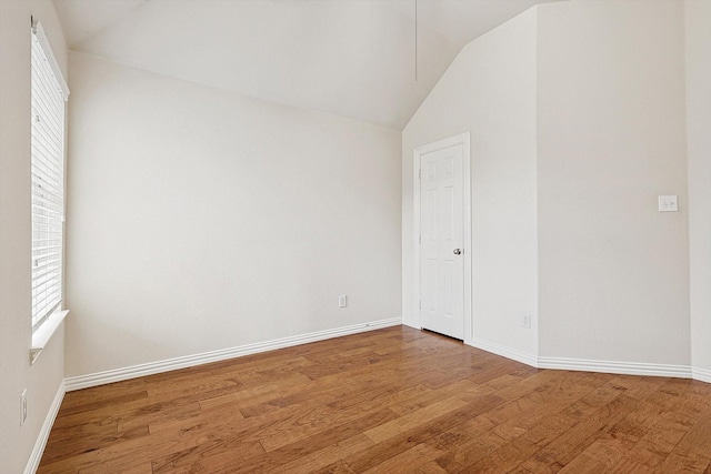 empty room featuring vaulted ceiling, a wealth of natural light, and wood-type flooring