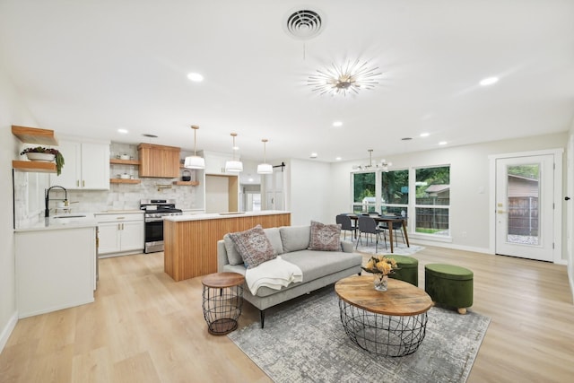 living room with a notable chandelier, light hardwood / wood-style flooring, and sink