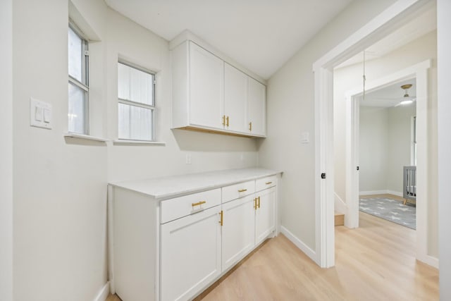 interior space with white cabinetry, ceiling fan, and light wood-type flooring