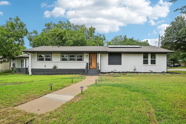 single story home with a front yard and solar panels