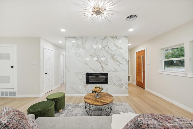 living room featuring light wood-type flooring and a high end fireplace