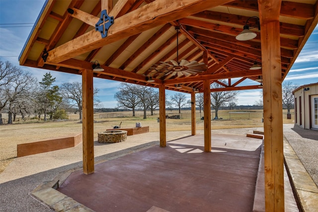 view of patio featuring ceiling fan, a rural view, a gazebo, and an outdoor fire pit