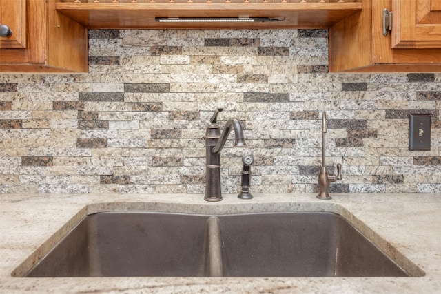 368 Hawkins Rd, Whitesboro, TX 76273 - kitchen view of a sink, tasteful backsplash, brown cabinetry, and light stone countertops