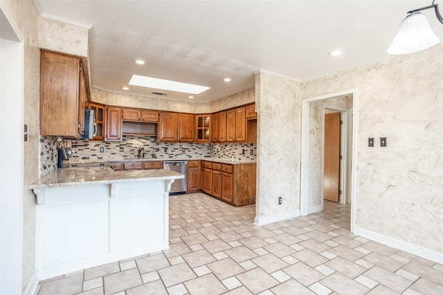 kitchen featuring decorative light fixtures, kitchen peninsula, a skylight, appliances with stainless steel finishes, and light stone countertops