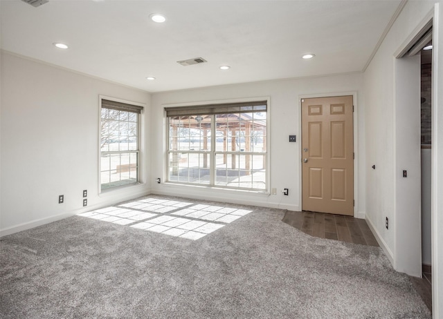 spare room with ornamental molding and dark colored carpet