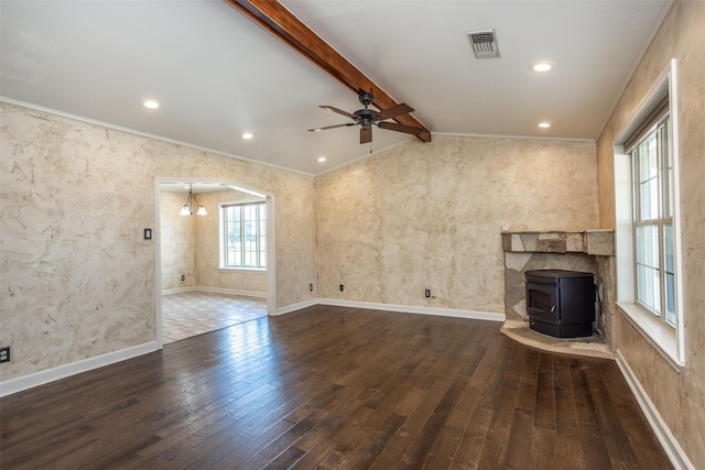 unfurnished living room featuring ceiling fan, dark hardwood / wood-style floors, vaulted ceiling with beams, crown molding, and a wood stove