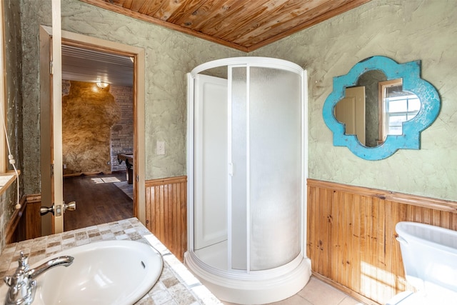 bathroom featuring sink, crown molding, wooden walls, a shower with door, and wooden ceiling