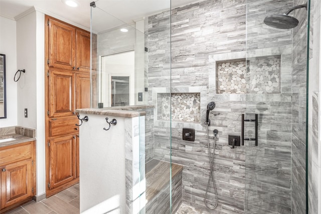 bathroom featuring tiled shower, vanity, and crown molding