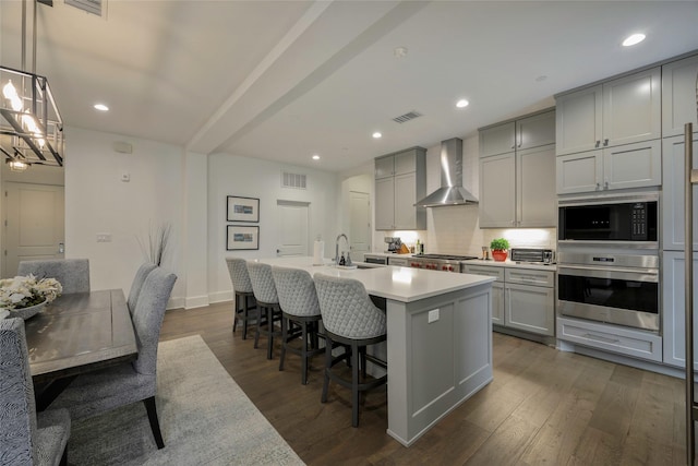 kitchen featuring dark hardwood / wood-style flooring, hanging light fixtures, gray cabinetry, and wall chimney exhaust hood