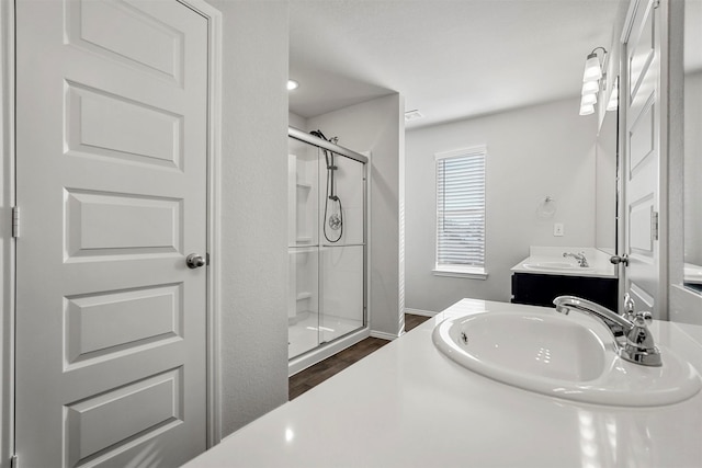 bathroom with wood-type flooring, walk in shower, and vanity