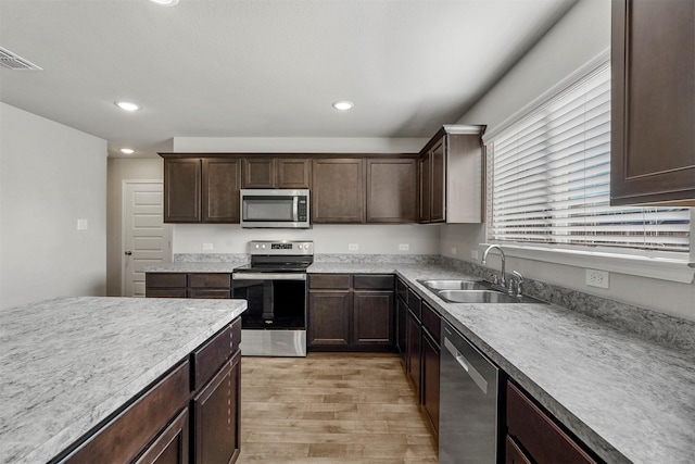 kitchen featuring light wood-type flooring, stainless steel appliances, dark brown cabinets, and sink