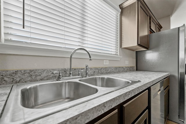 kitchen with appliances with stainless steel finishes, dark brown cabinets, and sink