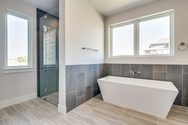 bathroom featuring plus walk in shower and tile walls