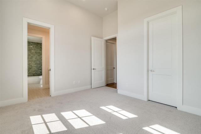 unfurnished bedroom with ensuite bathroom and light colored carpet