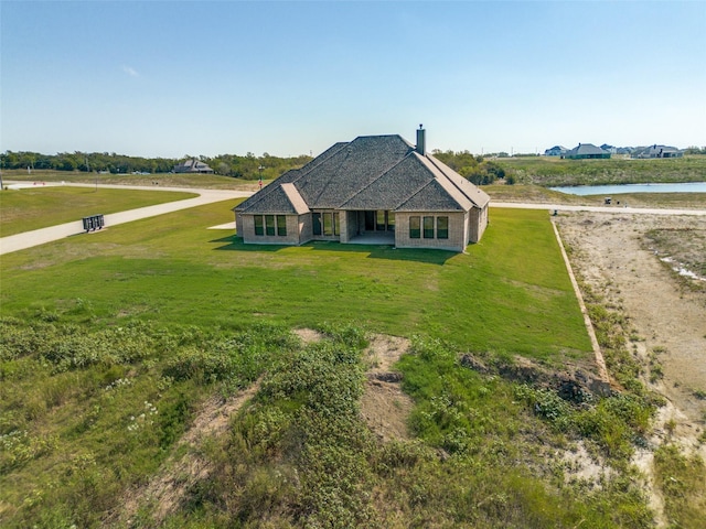 view of front of home with a front lawn and a water view