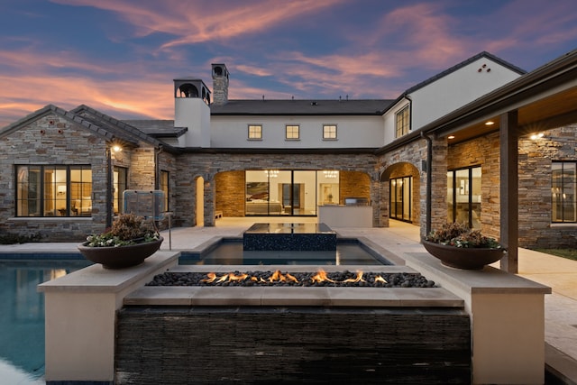 back house at dusk with a patio and a fire pit