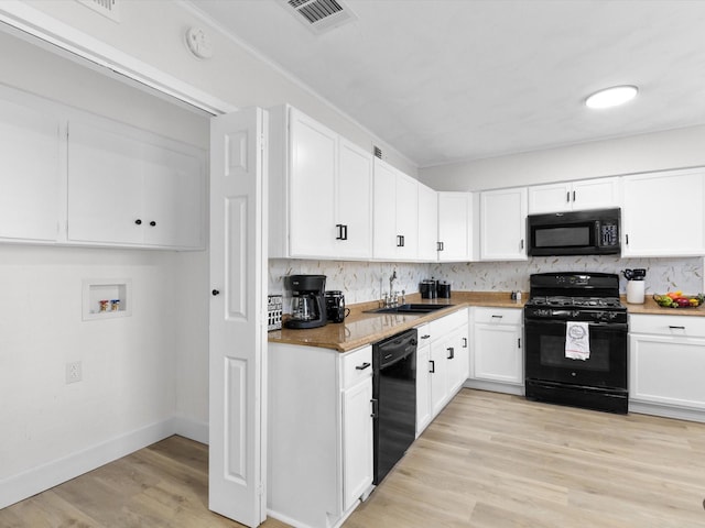 kitchen with light hardwood / wood-style floors, backsplash, black appliances, white cabinets, and sink